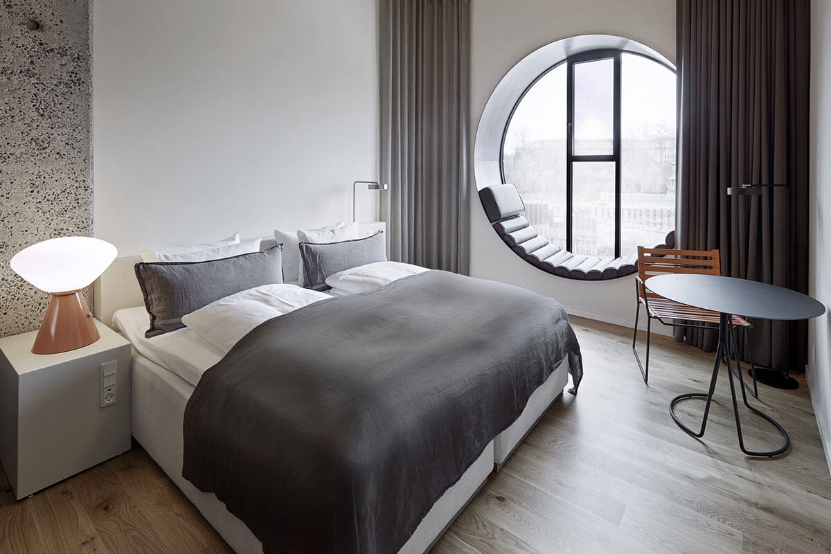 Ein typisches Hotelzimmer mit Doppelbett und einem großen runden Fenster.
