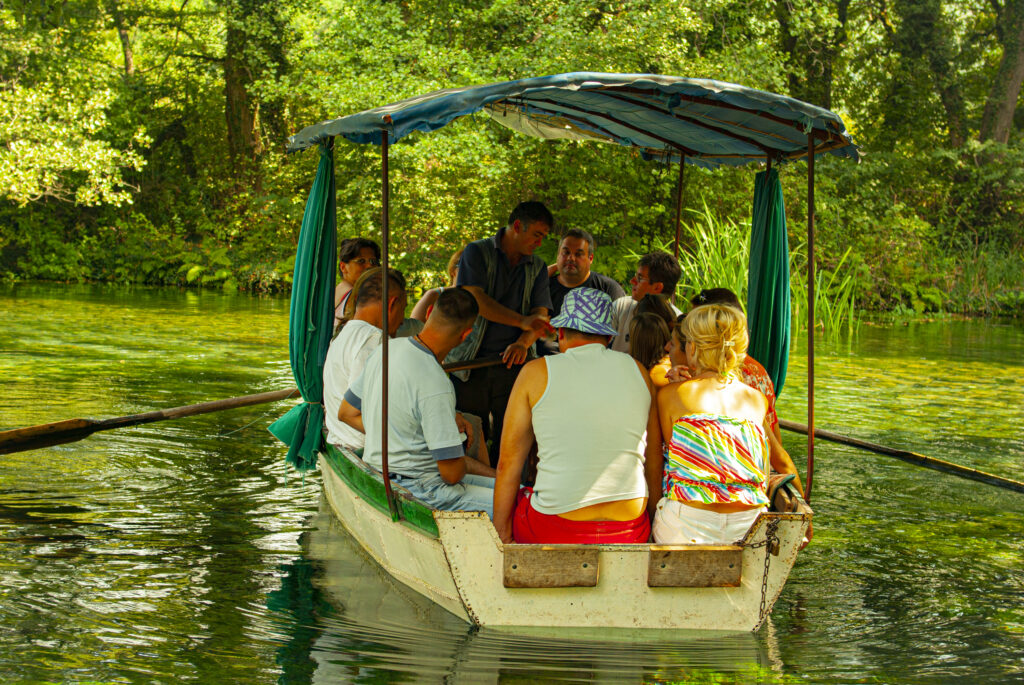 Eine kleines Ruderboot mit ca. 15 Leuten fährt über den unterirdischen Quellen des Ohridsee.