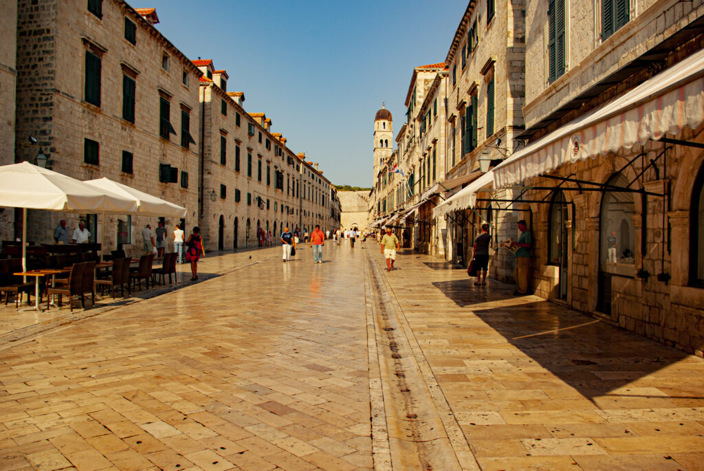 Der Stradun - die prachtvolle Hauptstraße der Altstadt in Dubrovniks. Eine Straße mit Marmor gepflaster eingerahmt von alten Häusern. Im Hintergrund ist der Turm des Franziskanerklosters zu sehen