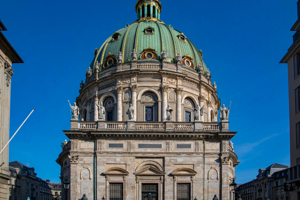 Blick auf die Frederiks Kirke mit ihrer patinierten grünen Kuppel, welche sich vor dem blauen Himmel abzeichnet.