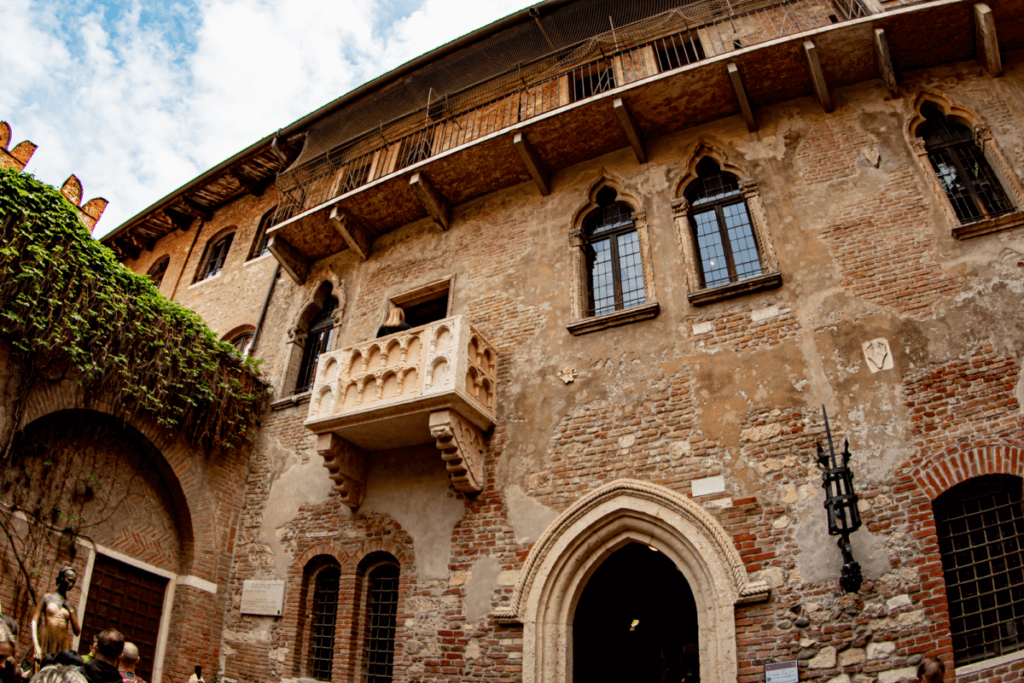 Eine Fassade im gotischen Backsteinstil mit einem steinernen Balkon.