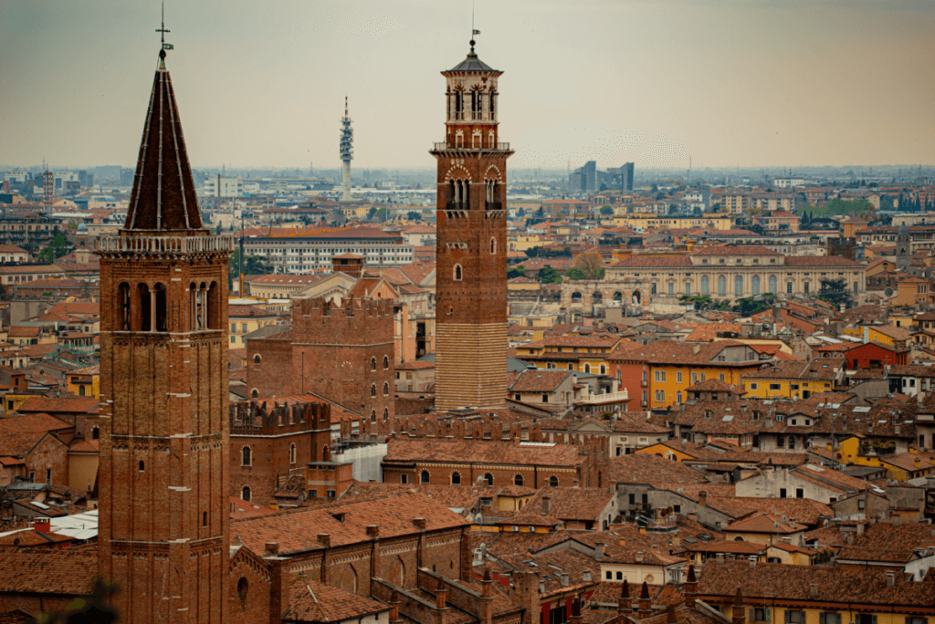 Der Blick über die Dächer der Altstadt in Verona. Im Mittelpunkt steht der Glockenturm des Torre dei Lamberti. Im Vordergrund der Turm der gotischen Backsteinbasilika von Sant’Anastasia.