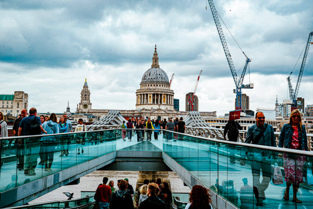 Im Mittelpunkt ist die Kuppel der Saint Pauls Cathedral zu sehen. Sie wurde über die Milleniumbrücke hinweg fotografiert. Auf der Brücke sind zahlreiche Menschen zu sehen.