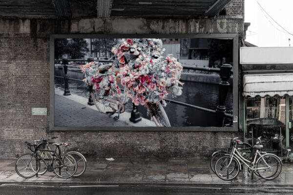 Ein Fahrrad mit Blumen geschmückt steht an einem Geländer vor einem Kanal.
