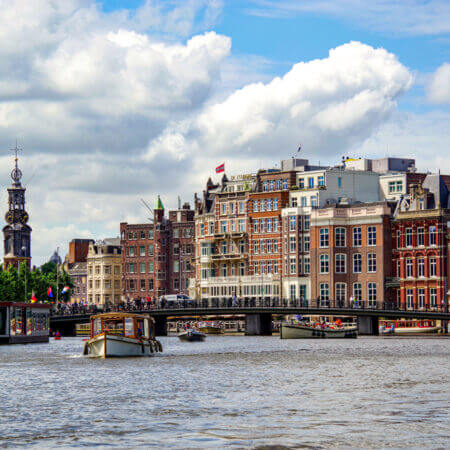 Munttoren, Amstel und die Halvemaansbrug vom Wasser aus betrachtet. Eine Skyline von Amsterdam mit typischen Hausfassaden.