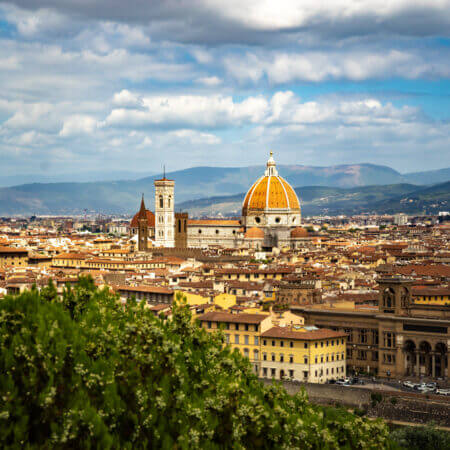 Die Mitten in der malerischen Altstadt erhebt sich ein architektonisches Meisterwerk, das die Jahrhunderte überdauert hat - die Kathedrale von Florenz. Über den Dächern der Alstadt erhebt sich die Kathedrale. Im Hintergrund sind die Berge zu sehen.