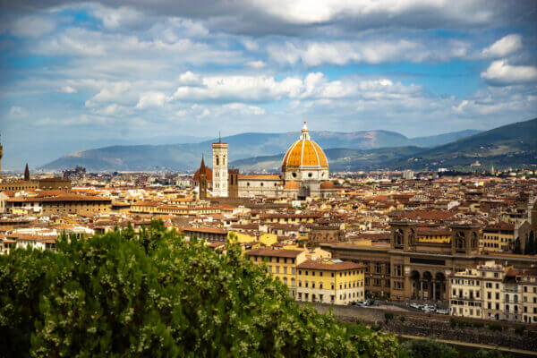 Die Mitten in der malerischen Altstadt erhebt sich ein architektonisches Meisterwerk, das die Jahrhunderte überdauert hat - die Kathedrale von Florenz. Über den Dächern der Alstadt erhebt sich die Kathedrale. Im Hintergrund sind die Berge zu sehen.
