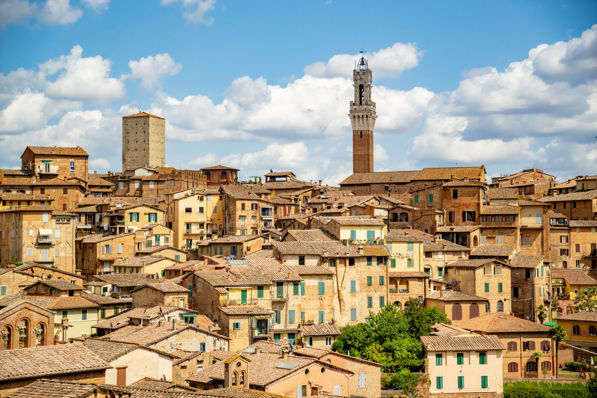 Über den Dächern von der Altstadt Sienas ragt der Torre del Mangia - ein 87 Meter hoher viereckiger Turm - heraus.