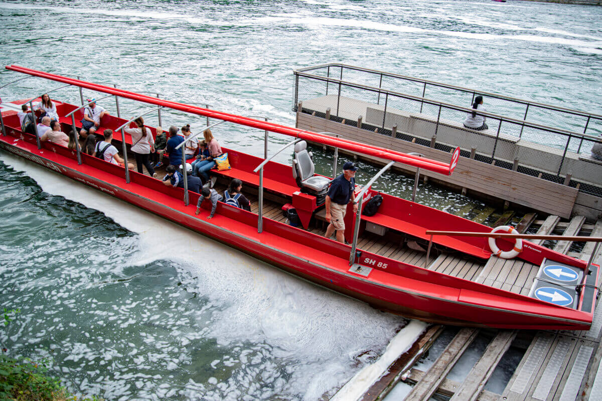 Ein Besucherboot in roter Farbe legt direkt von den Rheinfällen an.