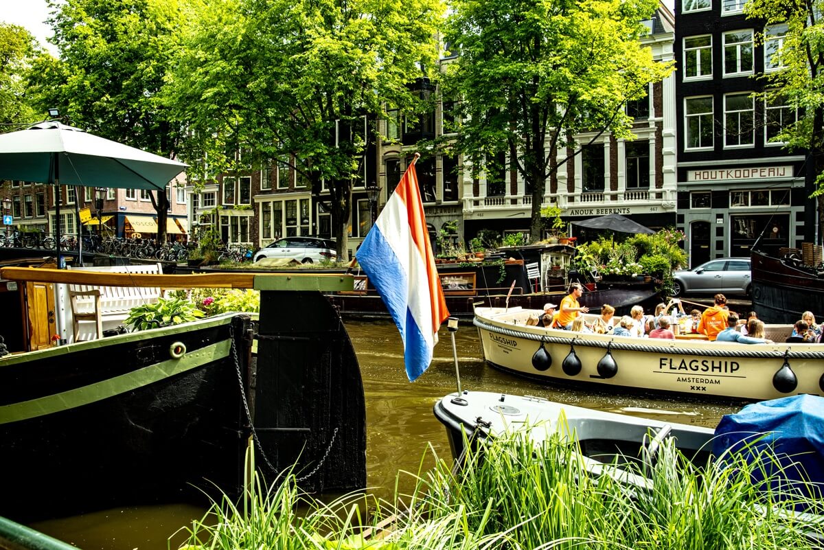 Die Holländische Flagge ziert das Heck eines Hausbootes welches in einer der zahlreichen Grachten liegt.