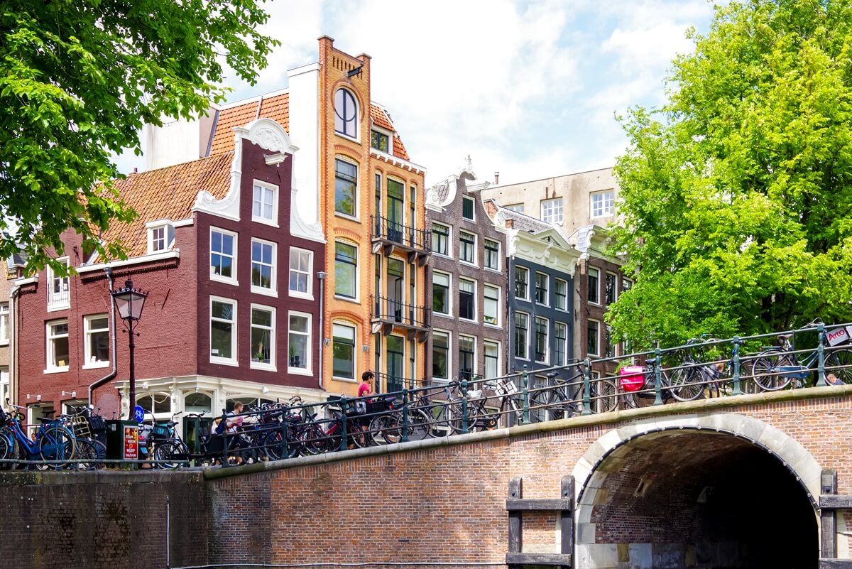 Schmal und schiefe Grachtenhäuser in Amsterdam von einem Kanal aus betrachtet. Mit Typischen Galgen, um schwere Dinge in die oberen Stockwerke zu bekommen, die nicht durchs Treppenhaus passen.
