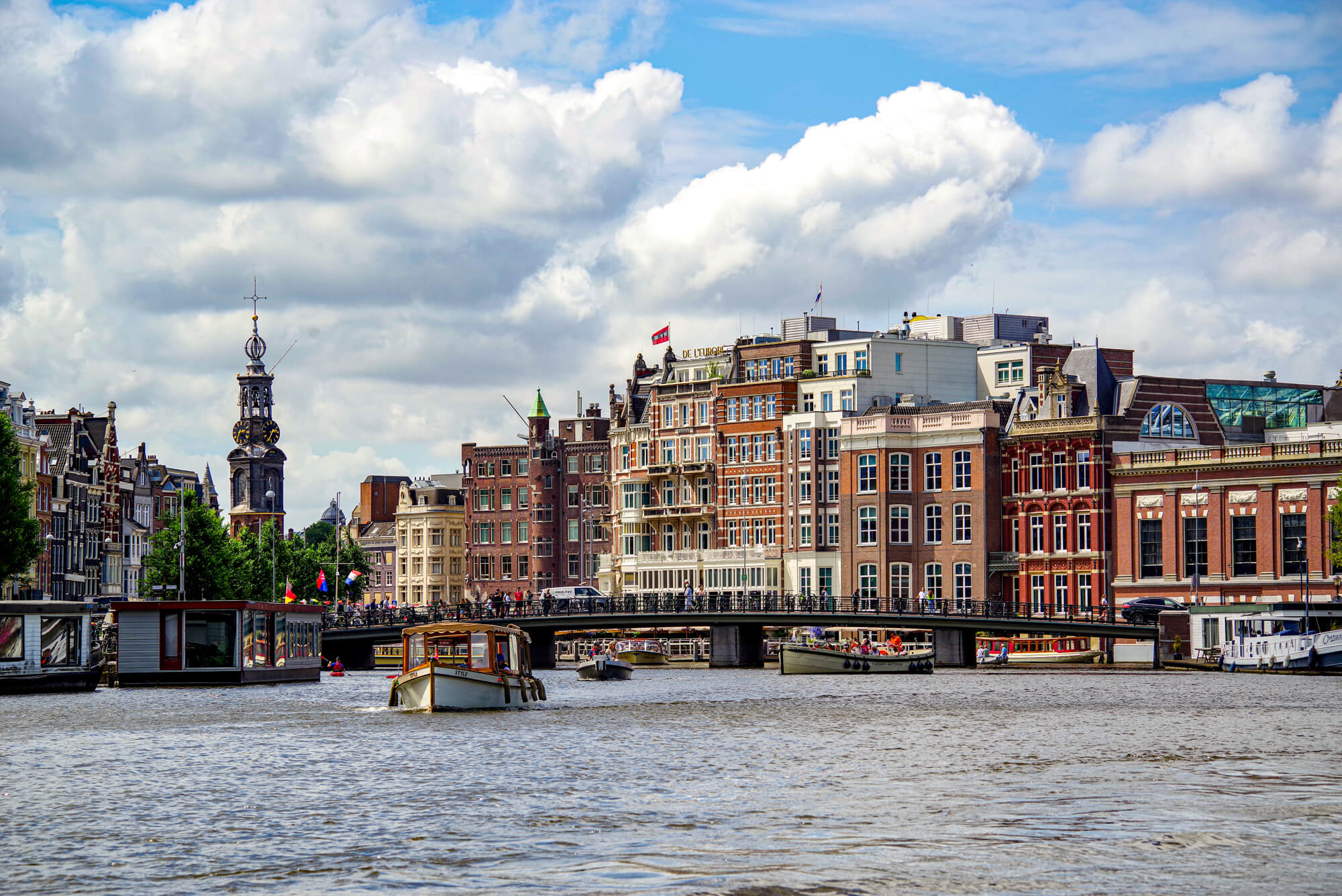 Die Amstel fliesst durch die Halvemaansbrug - die zu den bekanntesten Brücken in Amsterdam gehört. Im Hintergrund sieht man typische Häuser von Kaufmannsfamilien und das bekannte Münztor.