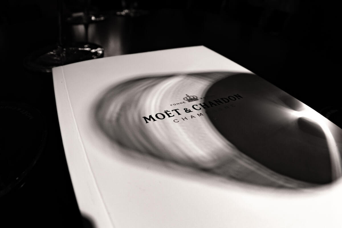Ein Schwarz-Weiß-Bild von einer Infobroschüre der Cahmpagner-Kellerei. Über den Cover fällt ein Schatten eines halbgefüllten Weinglases