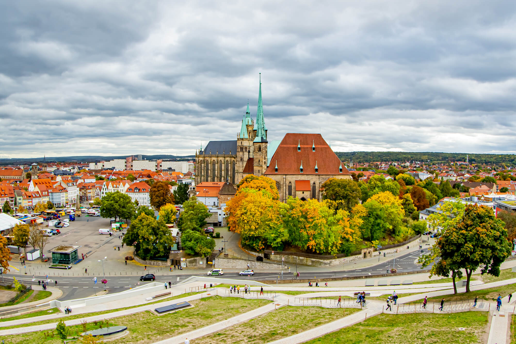 Der Dom von Erfurt von der Zitadelle Petersberg aus betrachtet. Es ist Herbst, die Bäume färben sich rot und gelb und der Himmel über dem Dom its grau.