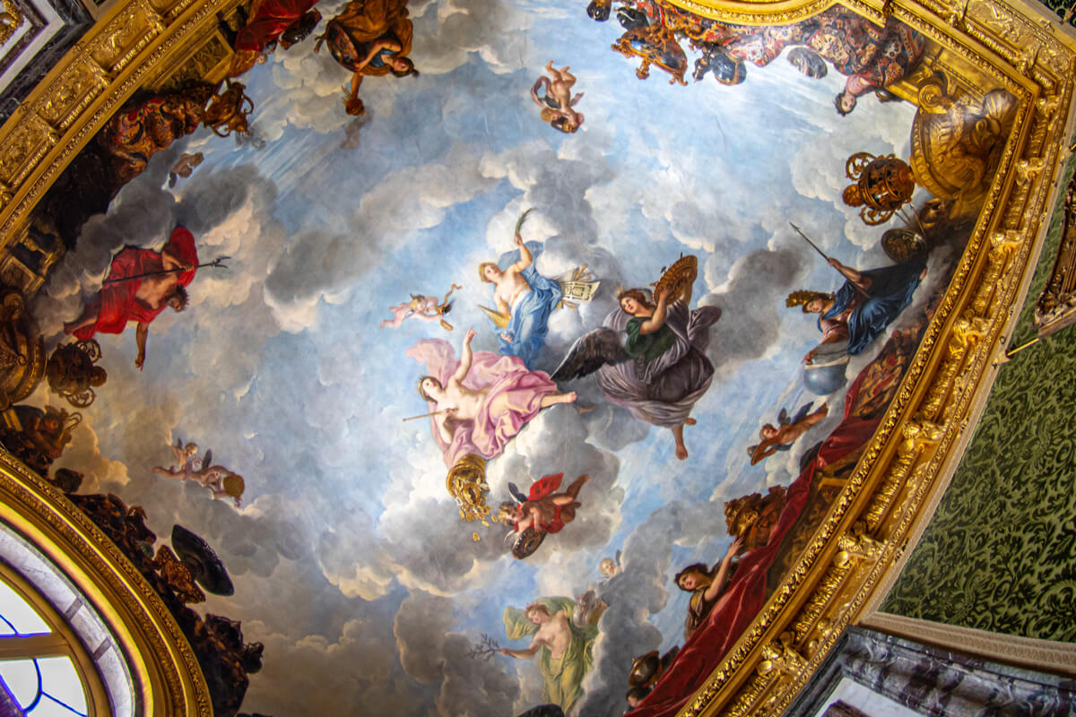 Eines der Deckengemälde im Schloss Versailles in pastelligen Farben gemalt und mit goldenen Stuck verziert.